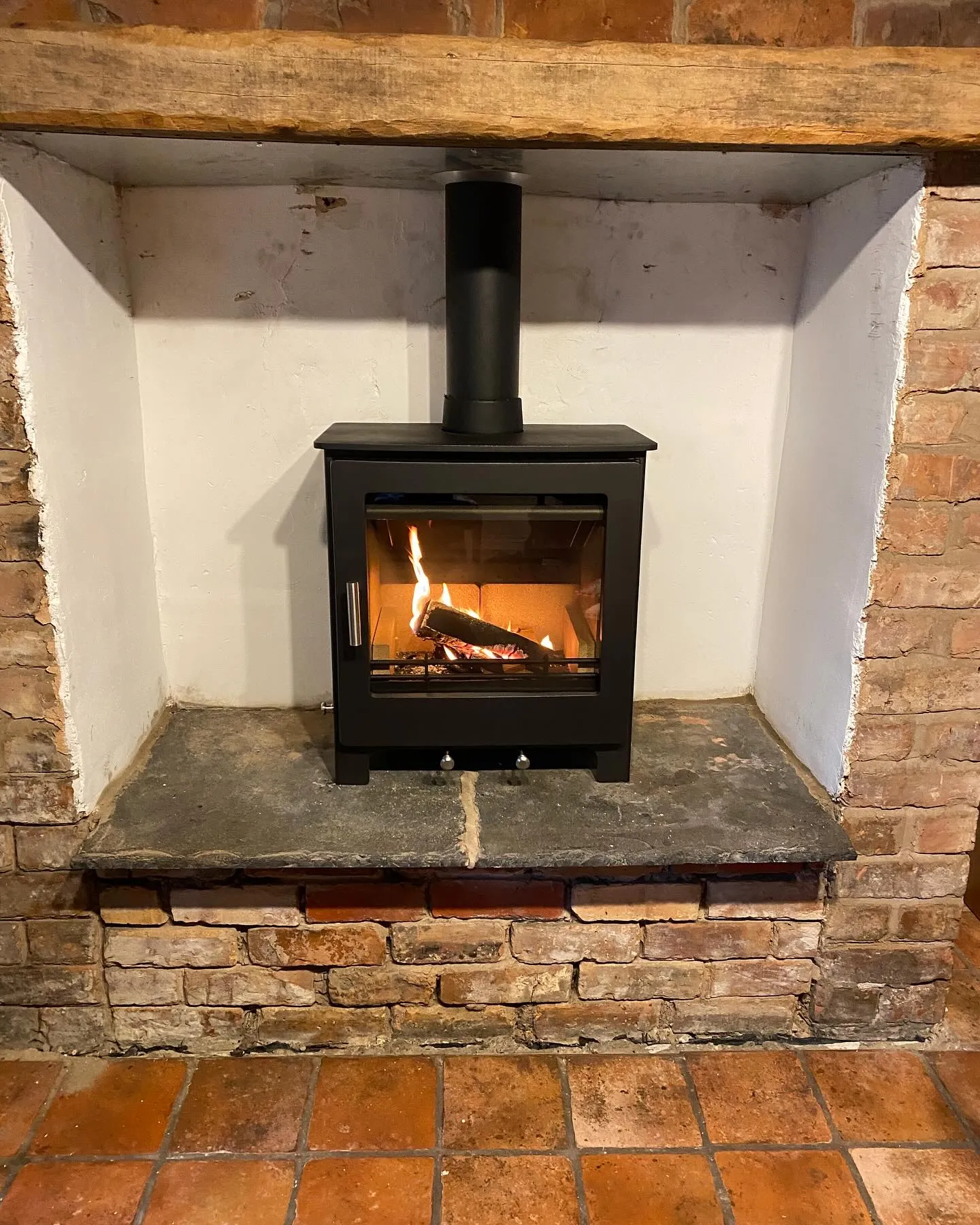 Modern stove in exposed brick fireplace