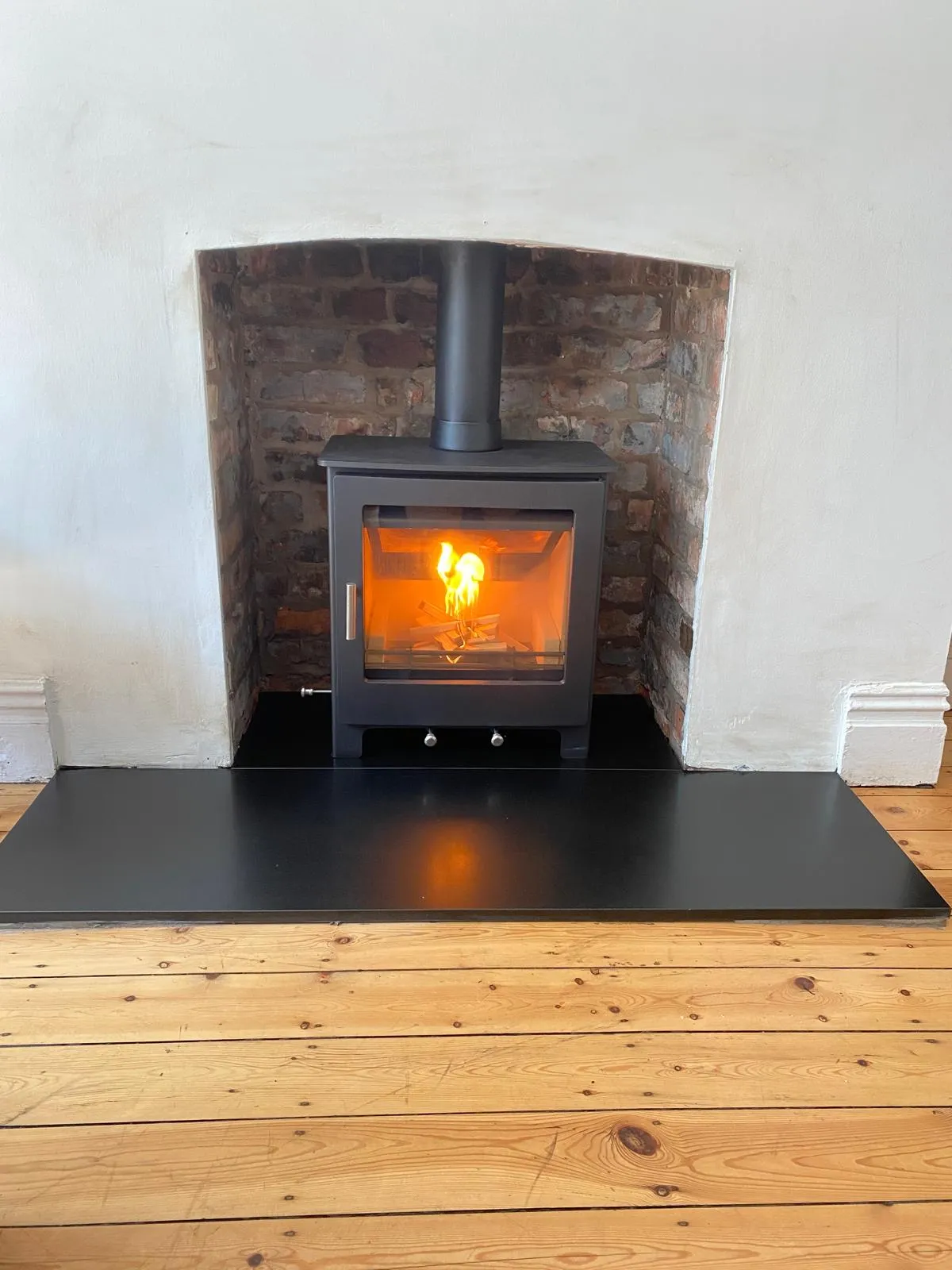Rustic stove installation in brick alcove