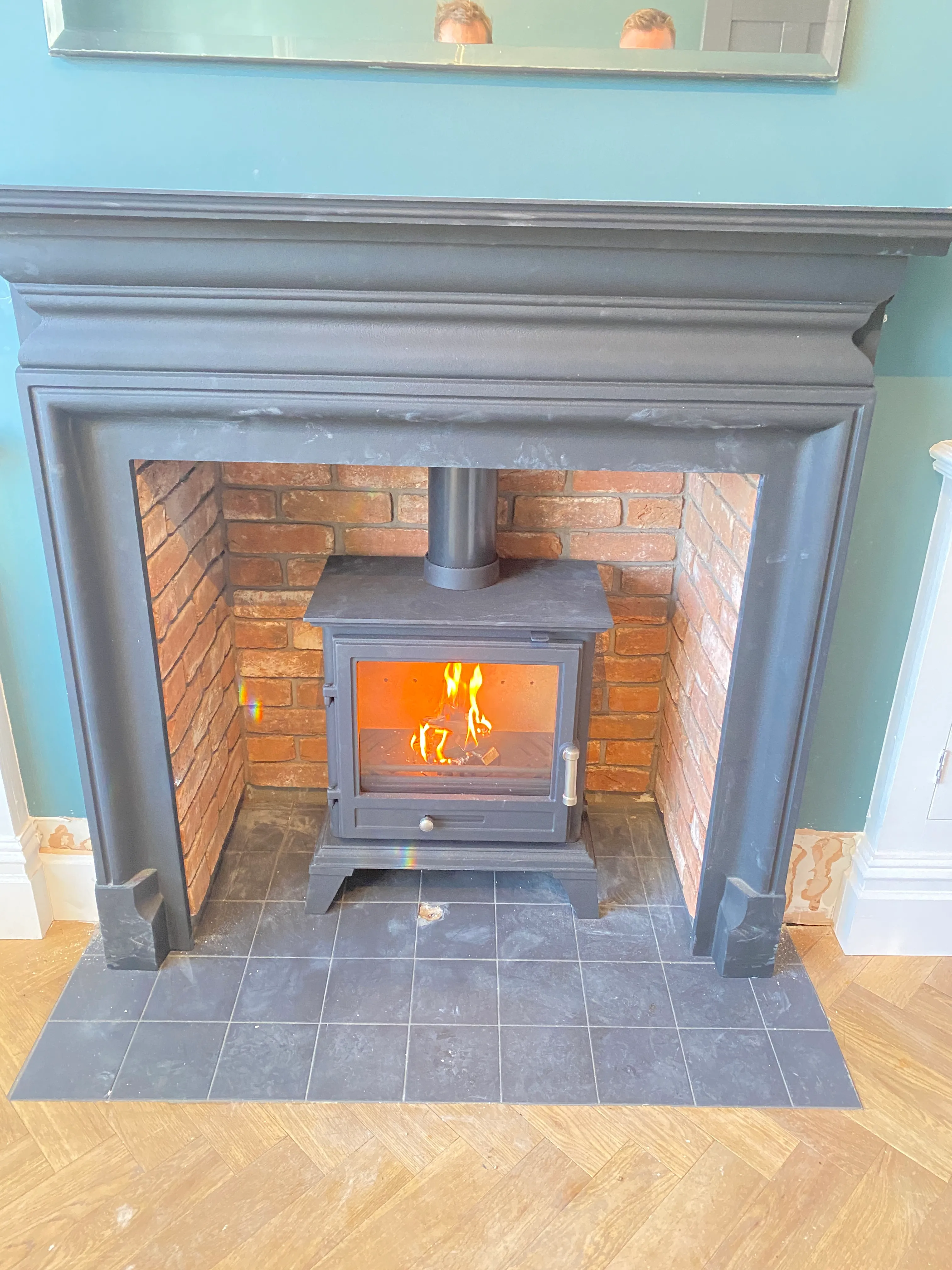 Stove set within an exposed red-brick fireplace