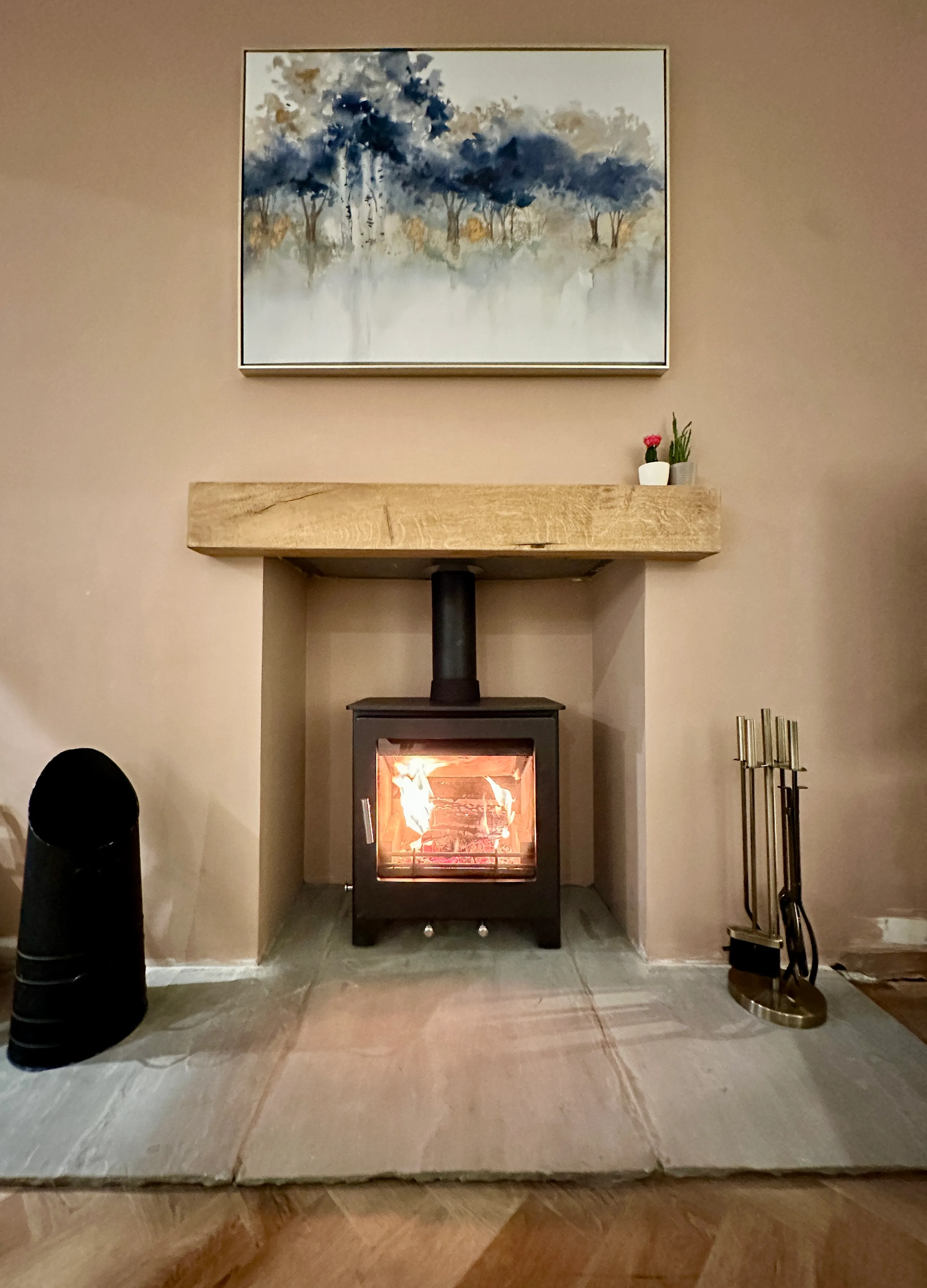Modern stove with oak beam mantel and landscape painting above