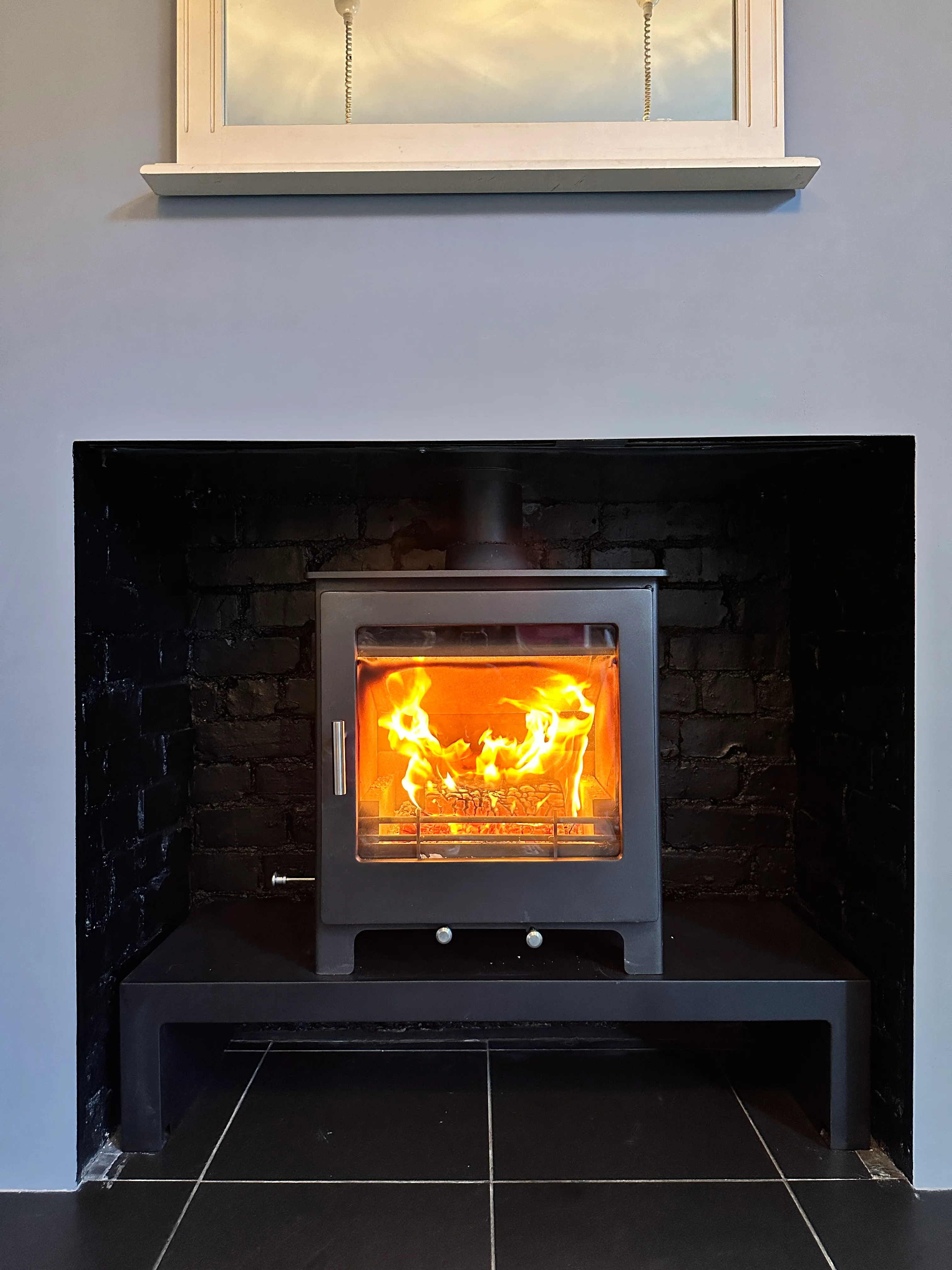 Inset stove in a blackened brick chamber with black marble surround